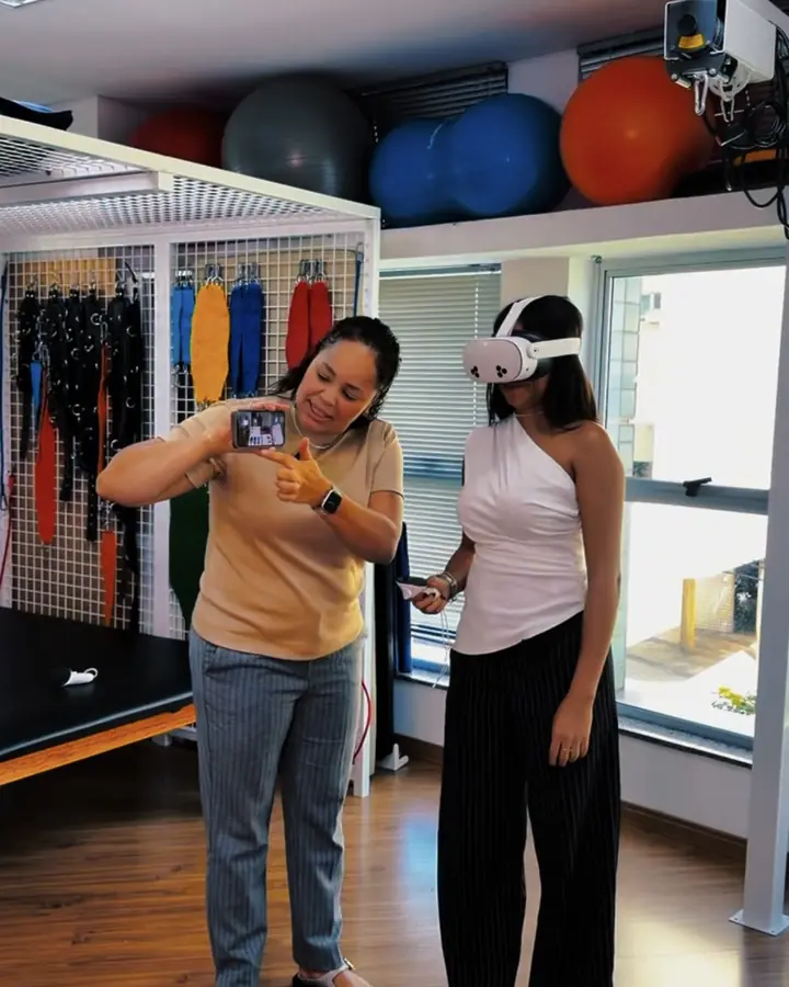 Fisioterapeuta orienta uma paciente no treino com realidade virtual